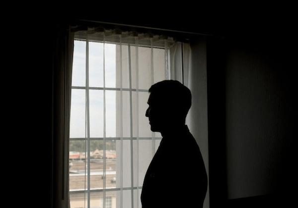 Man Standing Alone by Window