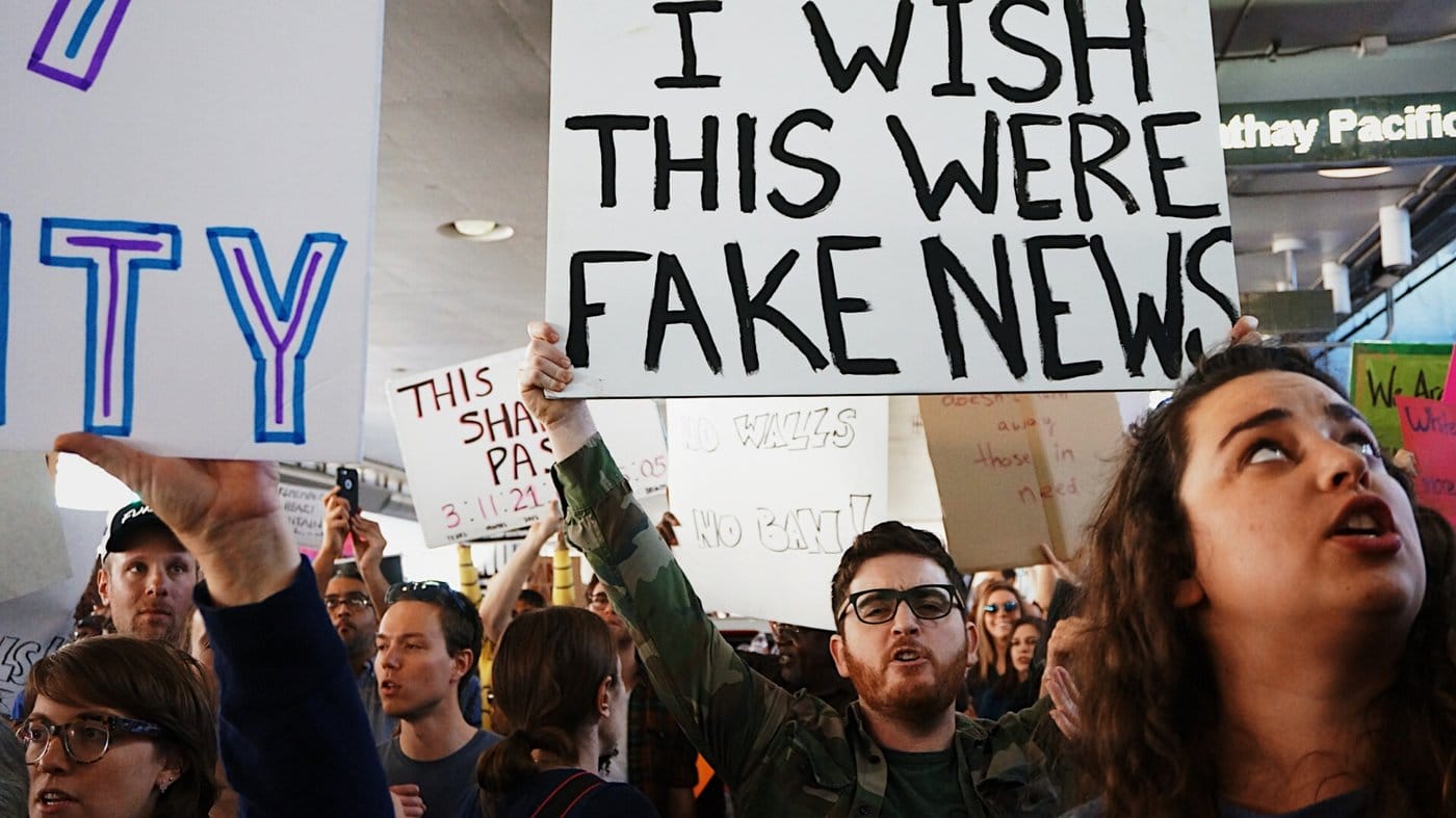 Protesters hold up signs protesting 