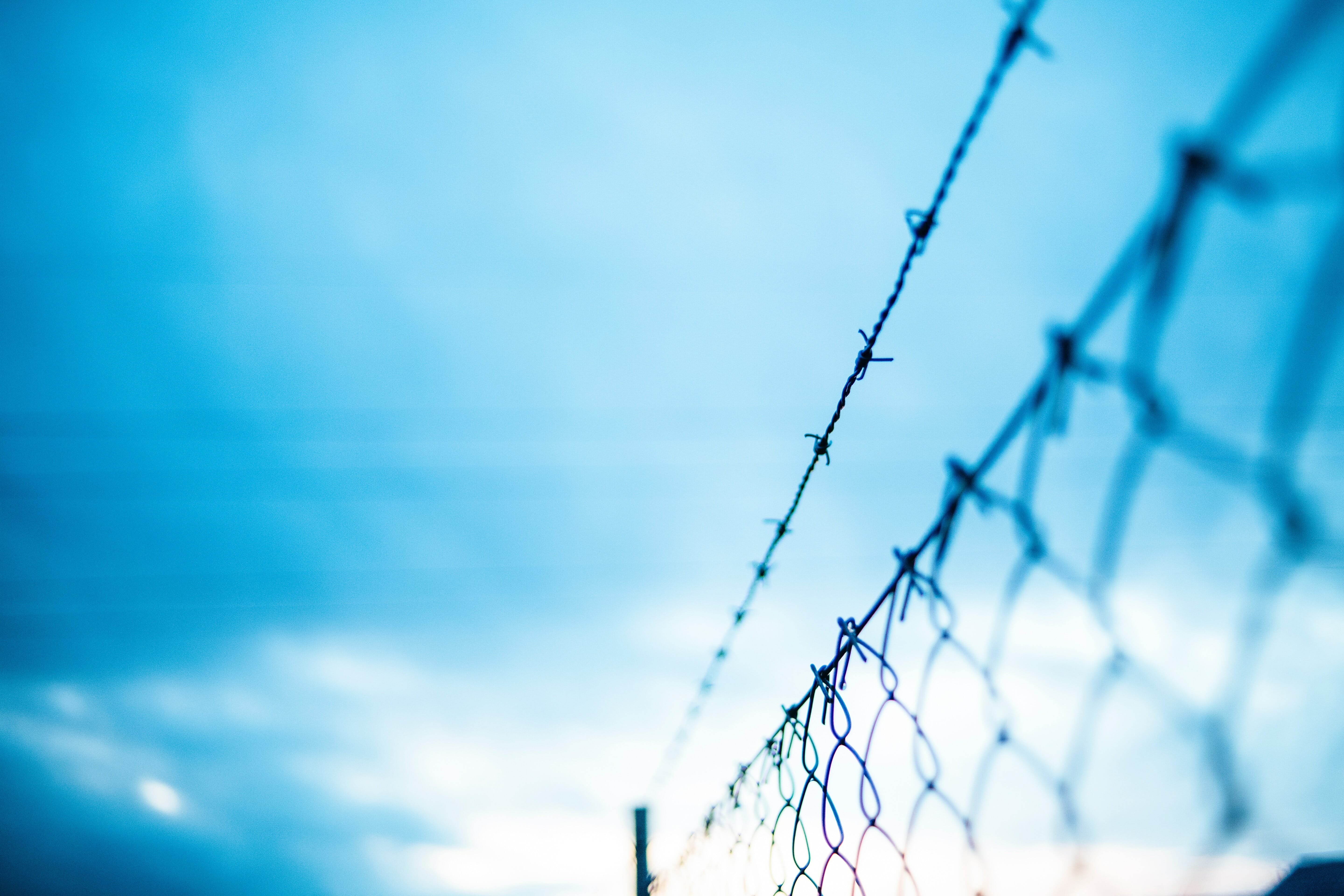 A barbed wire fence set against a cloudy sky. 