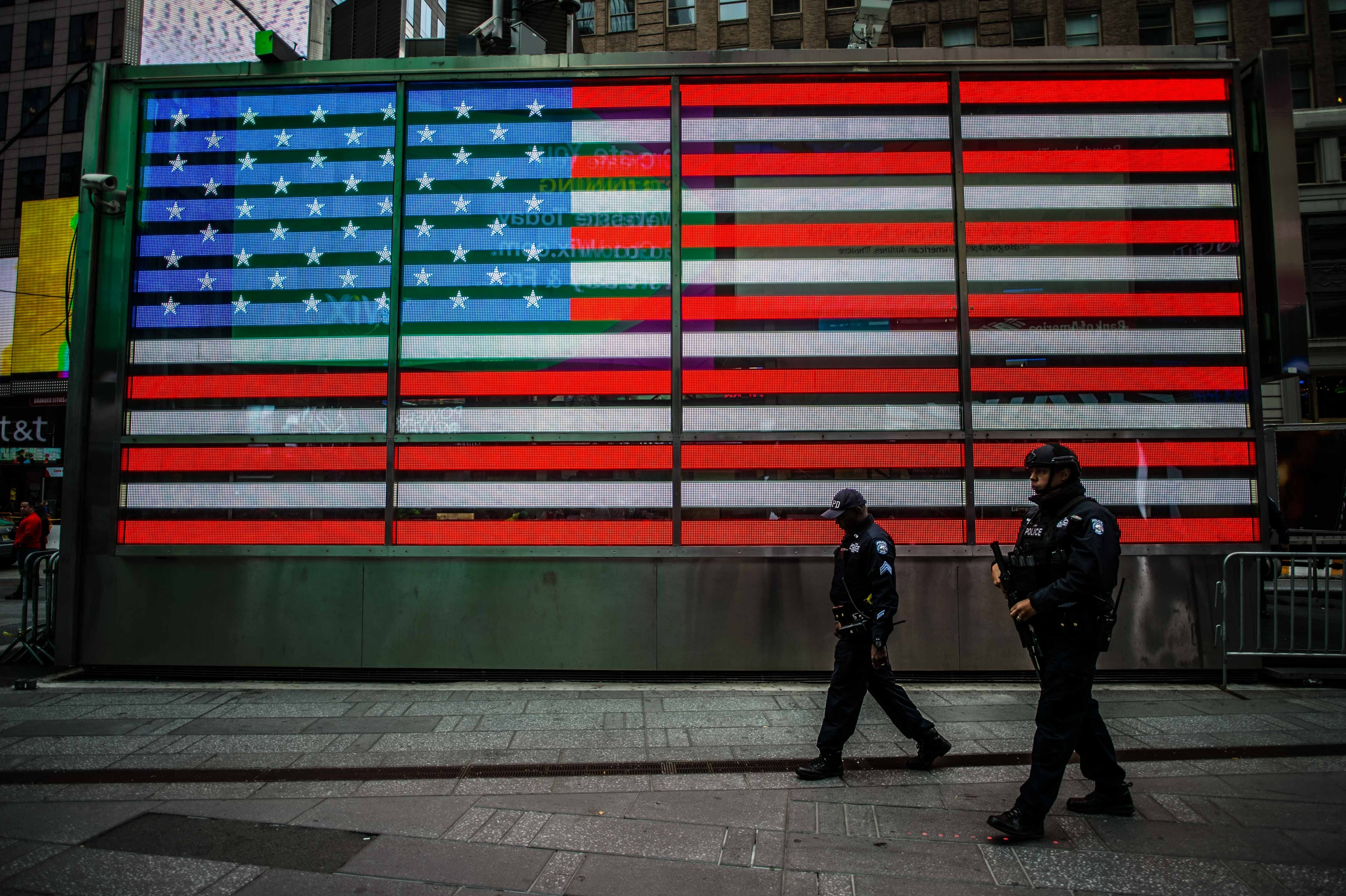 Police officers walking past an American flag. 