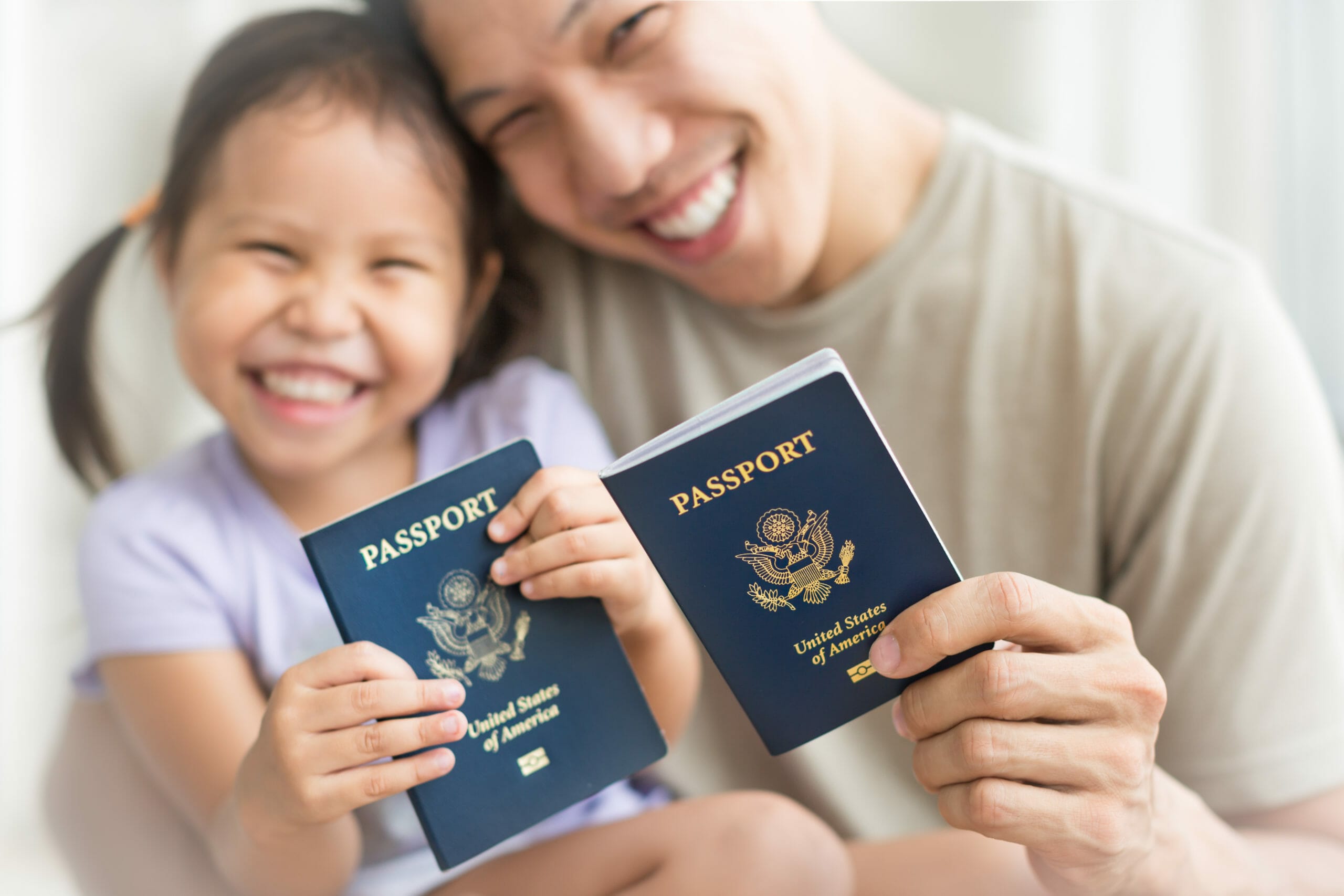 Asian dad and daughter holding amercian passports with pride. Immigration citizenship 