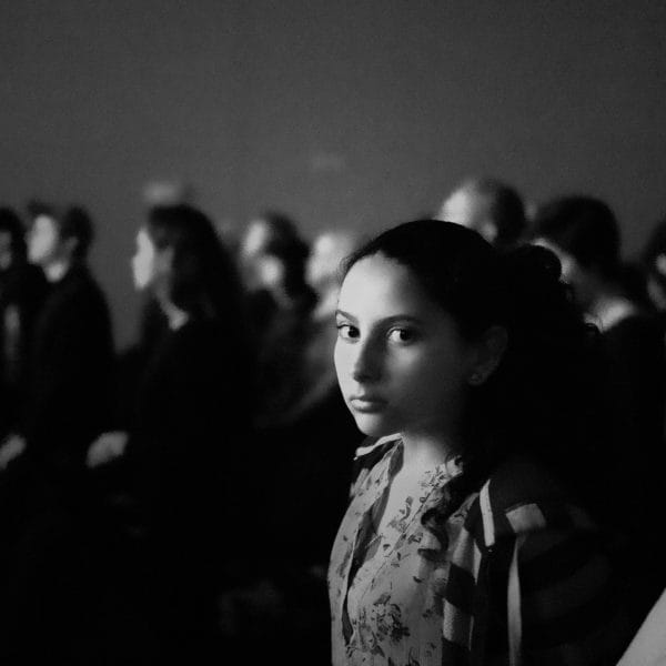 A girl sitting in the crowd.