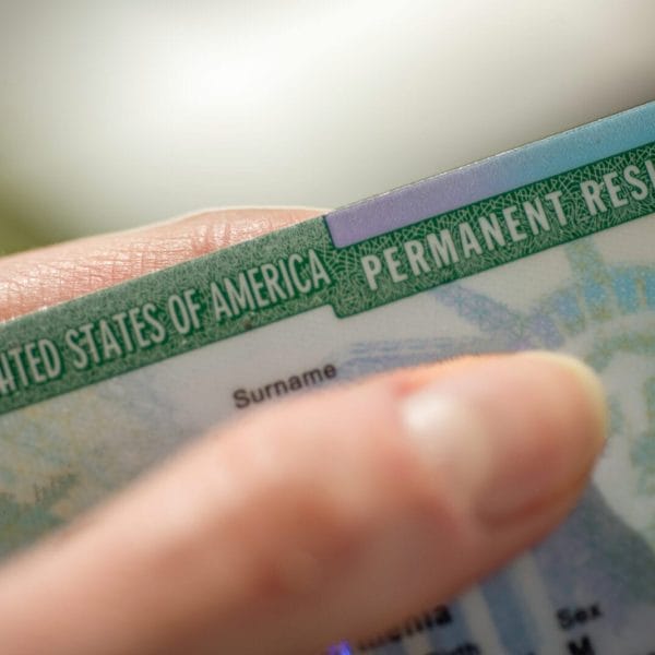photograph of a woman's hand holding a green card in advance of the uscis price increase