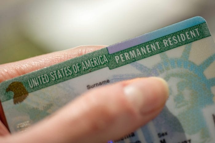 photograph of a woman's hand holding a green card in advance of the uscis price increase